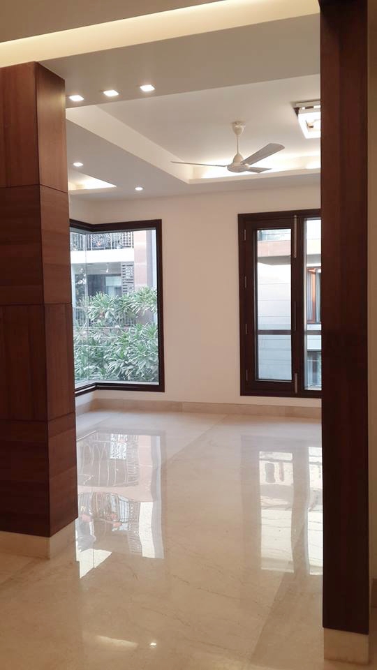 Light-filled living area with warm wood accents and custom partition — Green Park Residence, South Delhi